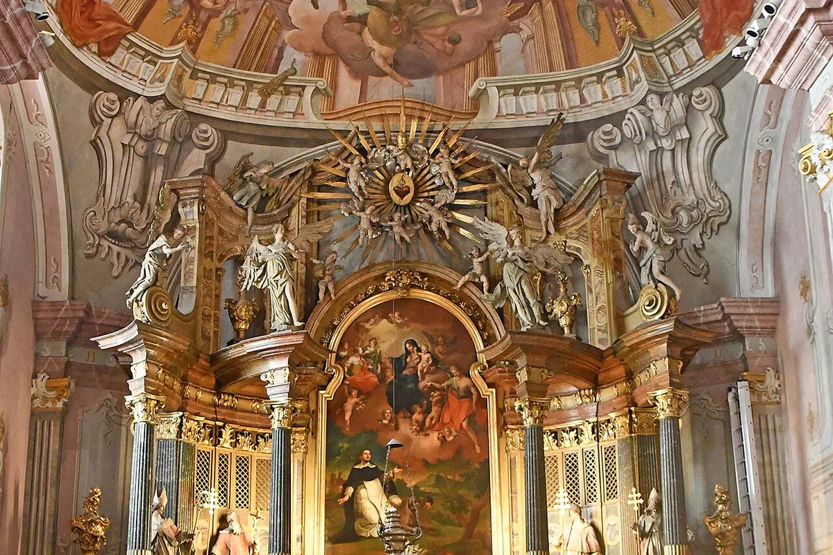 Ein vergoldeter Barockaltar in einer Budapester Kirche, gerahmt von gedrehten Säulen und bekrönt von einer goldenen Sonnenstrahlenkranz